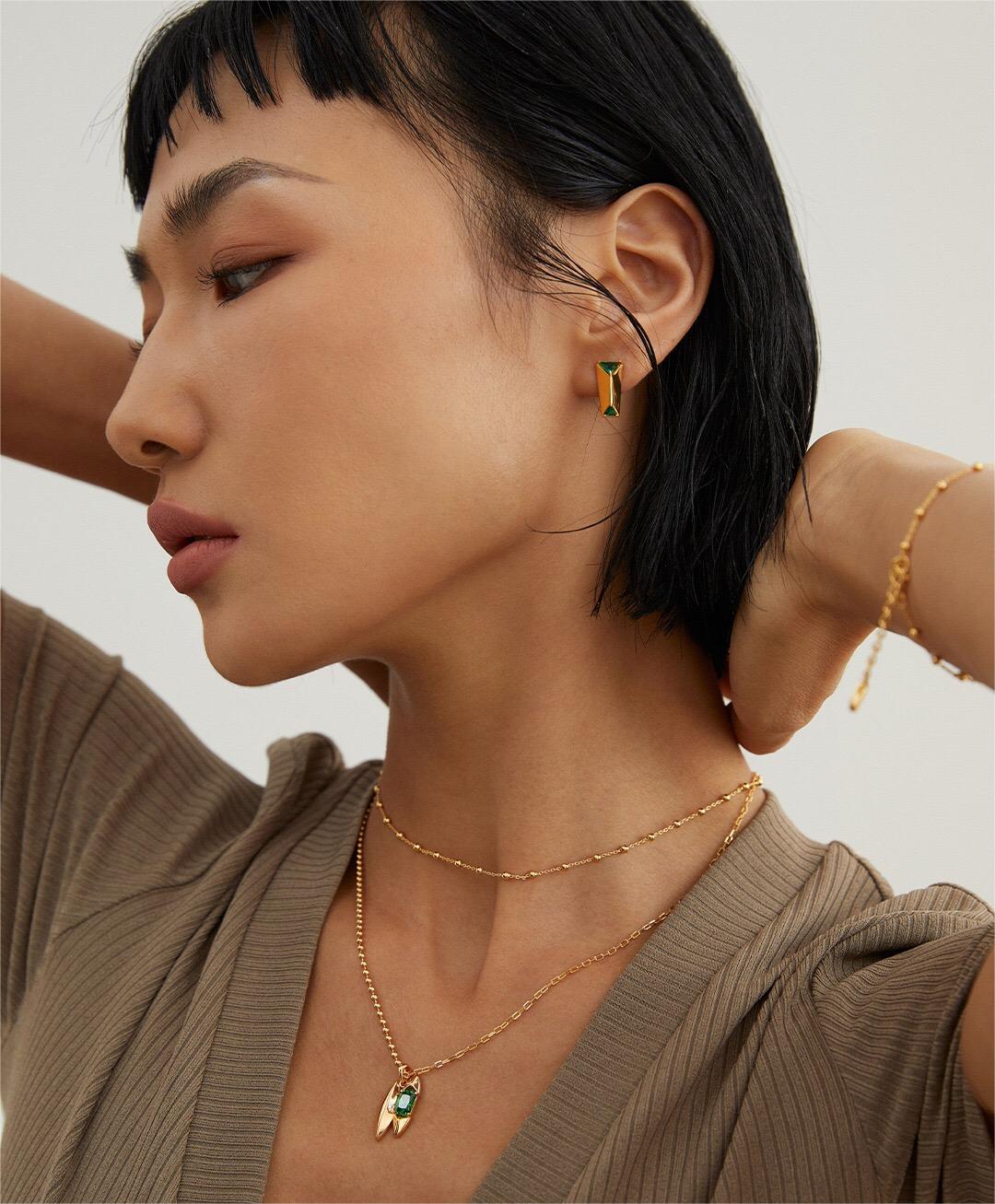 Side profile of model wearing Handmade Green Zircon Necklace layered with a gold chain, styled with matching green zircon earrings.