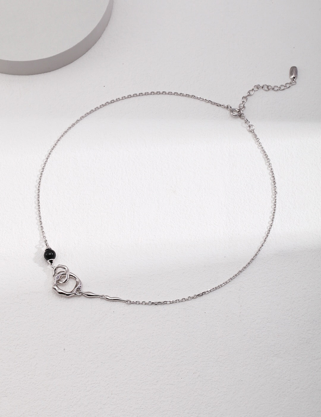 Silver Roundness Hollow Round Black Onyx Necklace featuring a black onyx bead and abstract circular pendant on an adjustable chain.