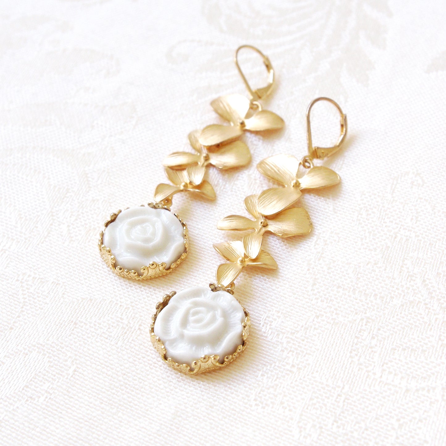 Porcelain Moonlight Rose and Triple Leaves Drop Earrings laid flat, showcasing handmade Danish craftsmanship and romantic floral design.