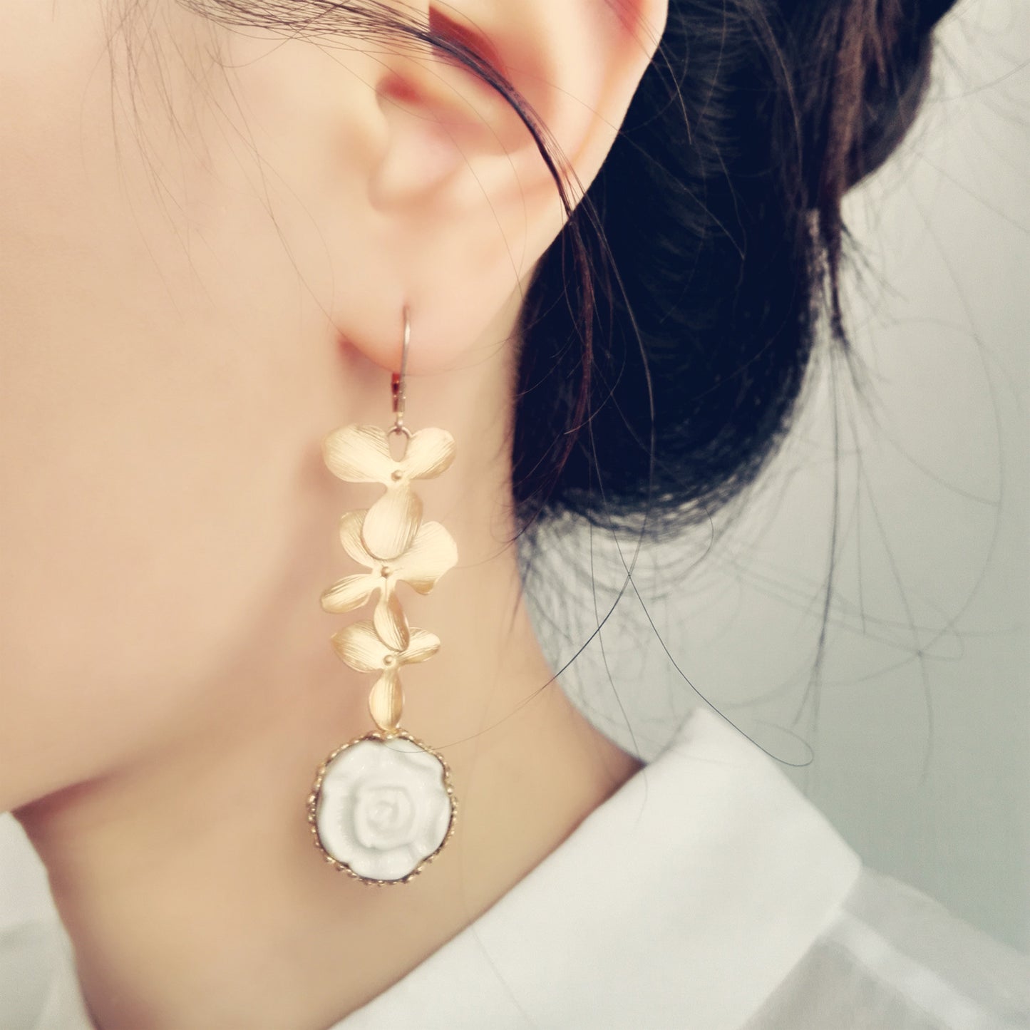 Model wearing Porcelain Moonlight Rose Drop Earrings with gold leaves and white rose, perfect for romantic and sophisticated looks.