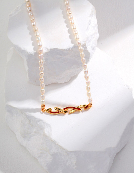 Awareness Ribbon Necklace with gold vermeil ribbon pendant and natural pearls, hypoallergenic and tarnish-resistant, displayed on white stones.