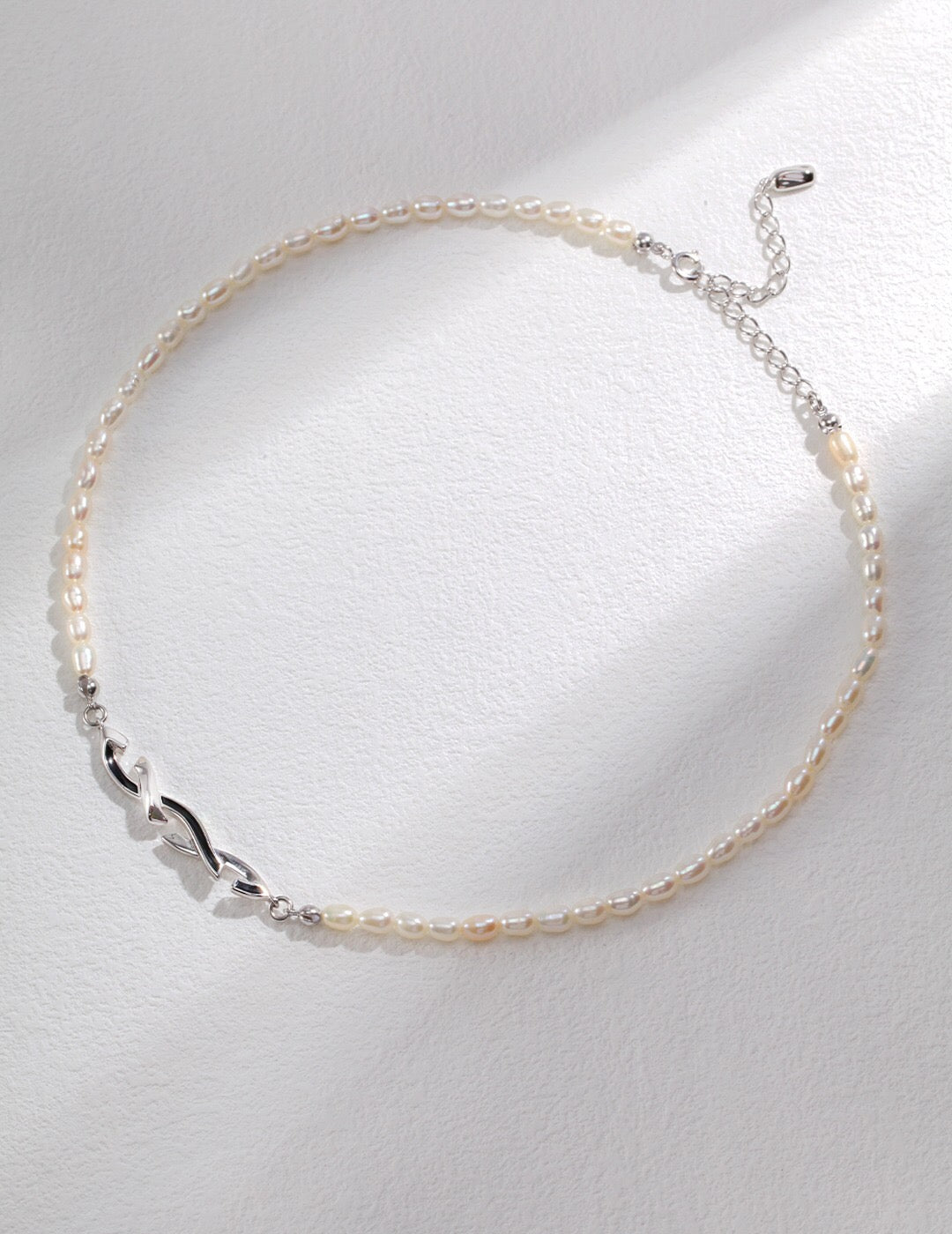 Full view of the Awareness Ribbon Necklace in silver with adjustable clasp, featuring natural pearls and geometric ribbon centerpiece.
