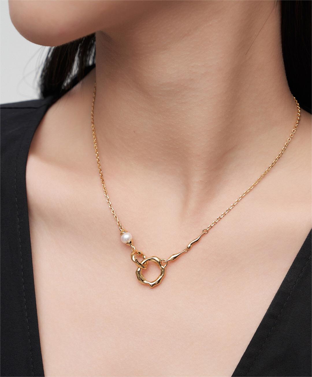Gold Roundness Hollow Round Pearl Necklace worn on model, showcasing elegant asymmetrical design with pearl and textured pendant.