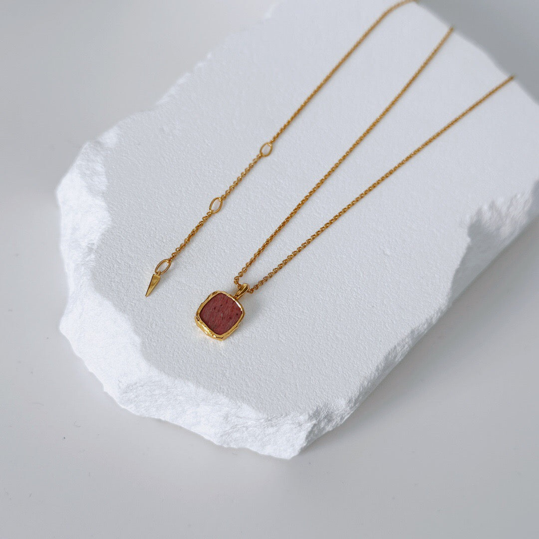 Natural Rhodochrosite pendant on Gold Healing Necklace with adjustable gold vermeil chain, styled on textured white display surface.