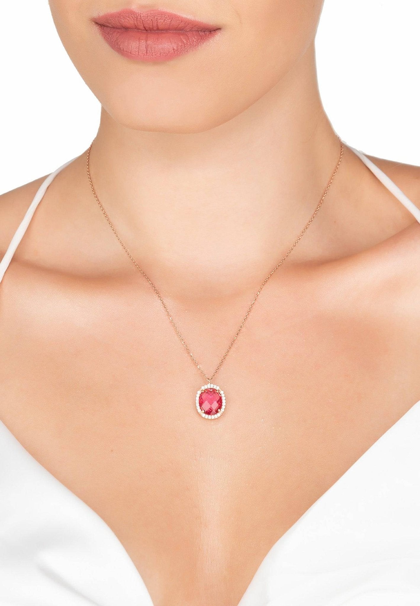 Beatrice Oval Gemstone Pendant Necklace in rose gold with a pink tourmaline centerpiece, worn on a model with a white V-neck top. Elegant and feminine jewelry piece.